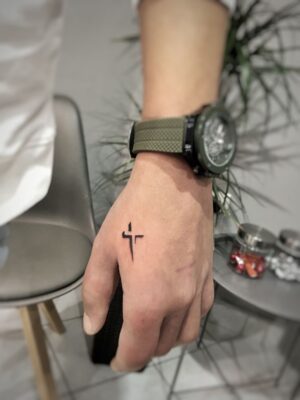 Hình xăm thánh giá mini trên mu bàn tay, phong cách blackwork, chi tiết rõ nét, ảnh HD.