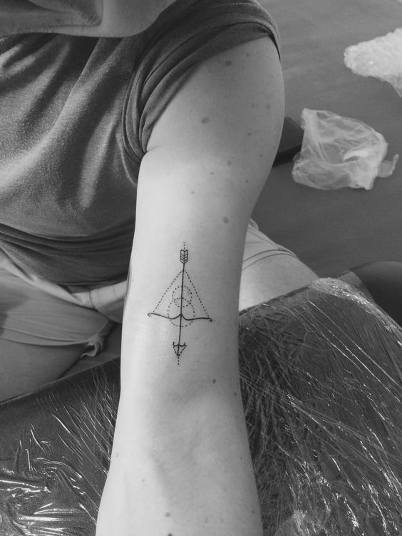 các mẫu xăm cung tên ở cánh tay Hình xăm cung tên mini trên cánh tay, phong cách blackwork, chi tiết rõ nét, ảnh độ phân giải cao.