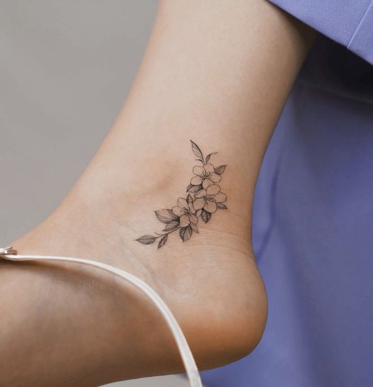 Hình xăm hoa mini trên mắt cá chân, phong cách blackwork, chi tiết rõ nét, độ phân giải HD.