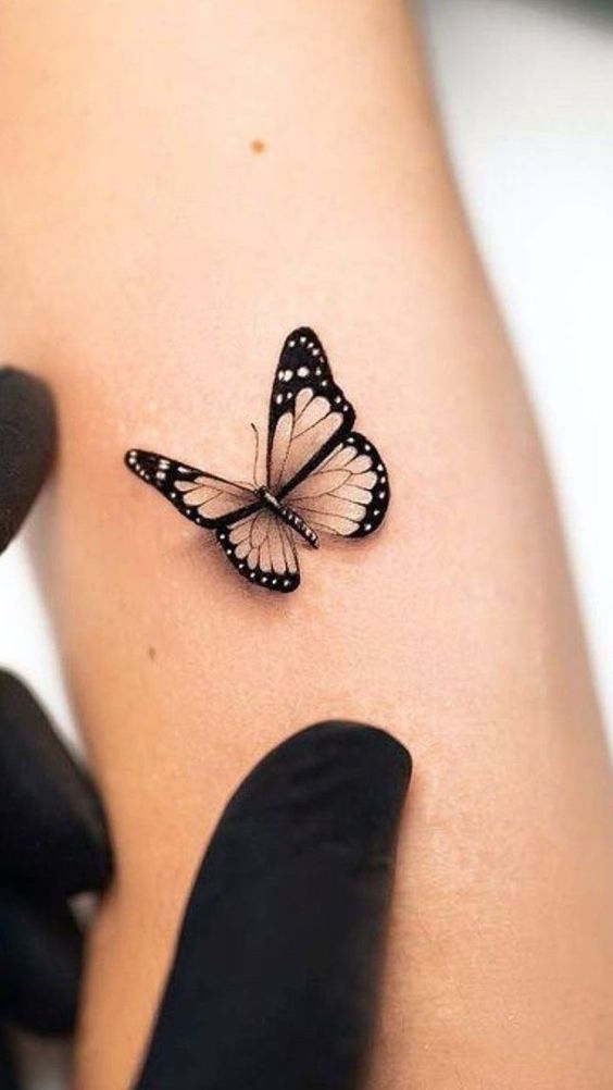 Hình xăm bướm mini trên cánh tay, phong cách blackwork, chi tiết sắc nét, độ phân giải HD.