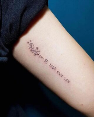 Hình xăm chữ và hoa mini trên cánh tay, phong cách blackwork, độ phân giải HD.