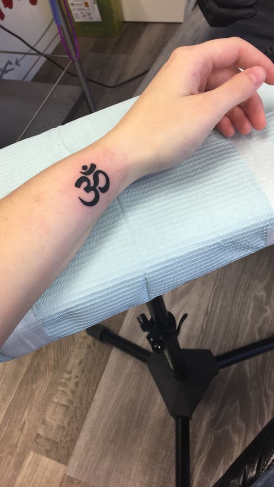 hình xăm chữ om cho khách tham khảo Hình xăm biểu tượng Om trên cổ tay, phong cách blackwork, ảnh chi tiết HD.