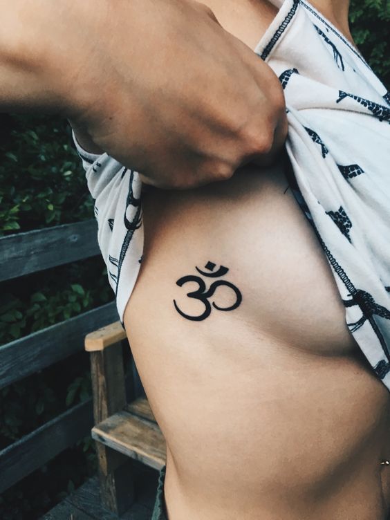 hình xăm chữ om mini ở ngực Hình xăm ký tự Om ở sườn, phong cách blackwork, độ chi tiết cao, ảnh chất lượng HD.
