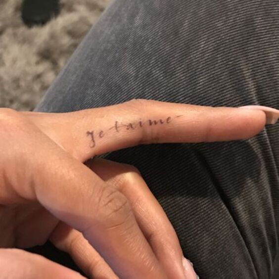 Hình xăm chữ "je t'aime" trên ngón tay, phong cách tối giản, độ phân giải HD.