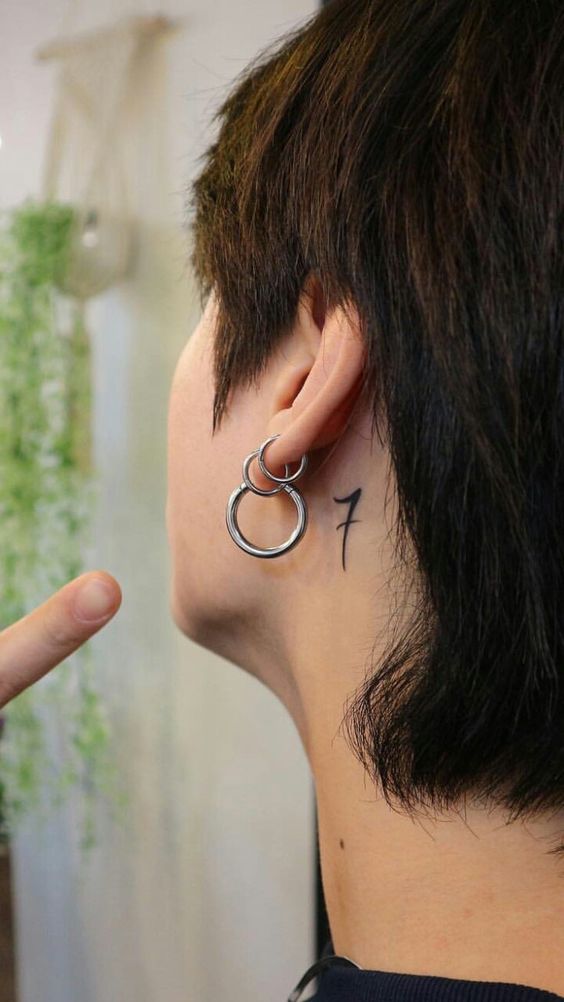 Hình xăm số "7" nhỏ sau tai, phong cách blackwork, độ phân giải HD.