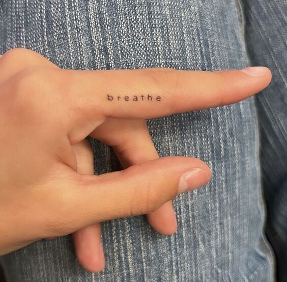 Hình xăm chữ "breathe" mini trên ngón tay, phong cách tối giản, ảnh chất lượng HD.