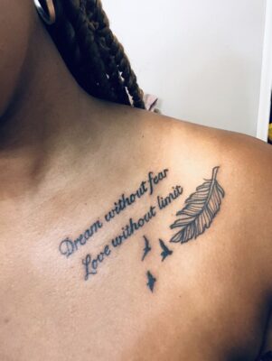 Hình xăm chữ và lông vũ trên vai, phong cách blackwork, chi tiết rõ nét, ảnh độ phân giải HD.