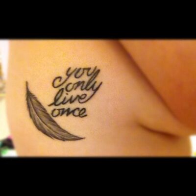 hình xăm chữ you only live once cho nữ Hình xăm chữ và lông vũ trên sườn, phong cách blackwork, độ phân giải HD.
