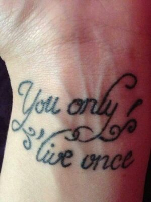 xăm chữ you only live once ở cổ tay Hình xăm chữ "You only live once" trên cổ tay, phong cách chữ nghệ thuật, ảnh độ phân giải HD.