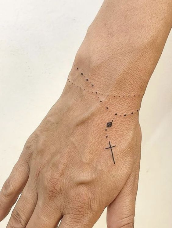hình xăm công giáo mini dạng vòng tay Hình xăm chuỗi hạt thánh giá mini trên cổ tay, phong cách blackwork, chi tiết rõ nét, độ phân giải HD.
