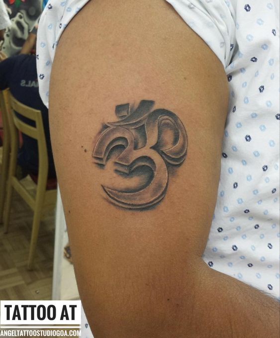 hình xăm cực đẹp cho nam Hình xăm ký tự Om trên bắp tay, phong cách blackwork, chi tiết sắc nét, độ phân giải HD.