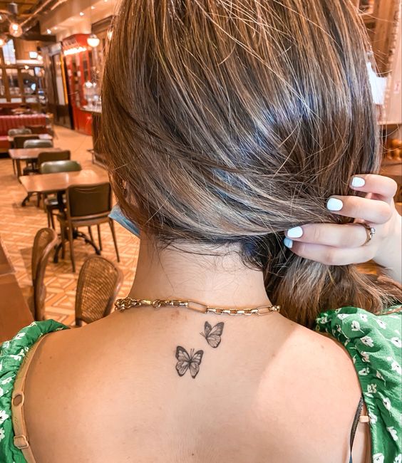 hình xăm đôi bướm mini nhẹ nhàng sau gáy Hình xăm bướm mini trên gáy, phong cách blackwork, chi tiết rõ nét, độ phân giải HD.