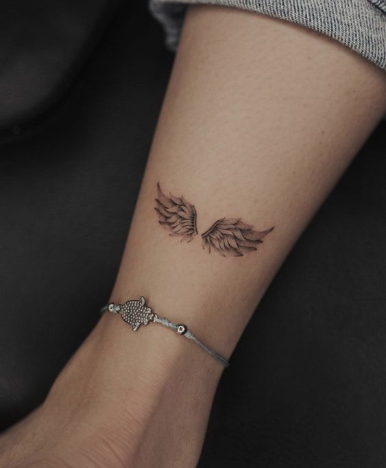 Hình xăm cánh thiên thần mini trên cổ tay, phong cách blackwork, chi tiết rõ nét, ảnh HD.