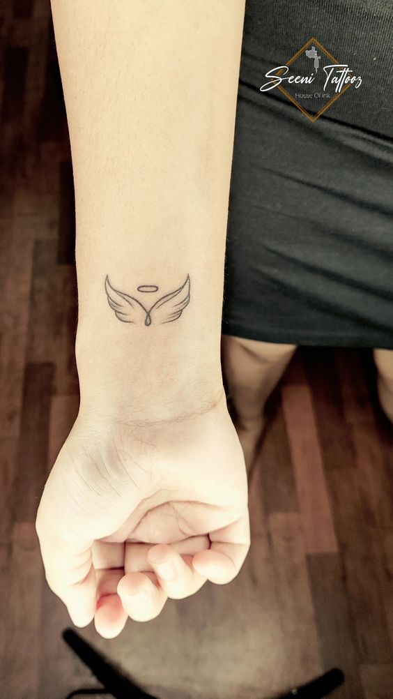 Hình xăm mini đôi cánh thiên thần ở cổ tay, phong cách blackwork, chi tiết rõ nét, ảnh HD.