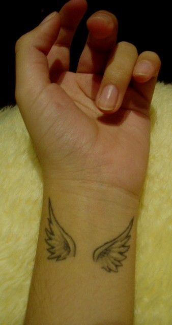 Hình xăm đôi cánh trên cổ tay, phong cách blackwork, chi tiết đơn giản, ảnh chất lượng HD.