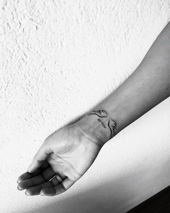 Hình xăm mini đôi cánh trên cổ tay, phong cách blackwork, ảnh đen trắng, độ phân giải HD.