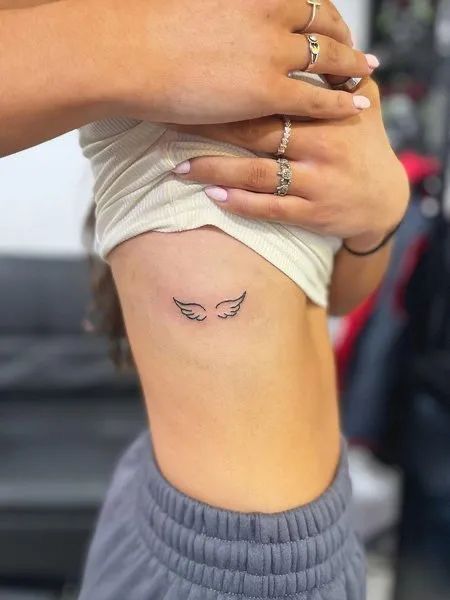 Hình xăm cánh thiên thần mini ở ngang sườn, phong cách blackwork, độ phân giải HD.