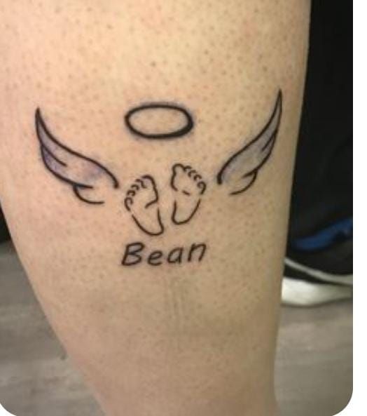 Hình xăm đôi cánh thiên thần, vòng tròn và dòng chữ trên chân, phong cách blackwork, ảnh HD.