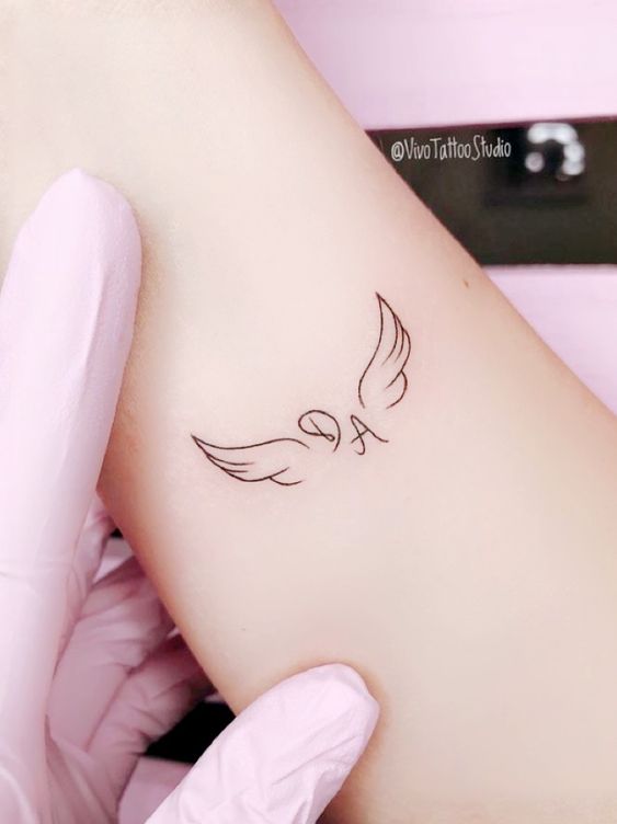 Hình xăm mini đôi cánh trên tay, phong cách blackwork, chi tiết rõ nét, độ phân giải HD.