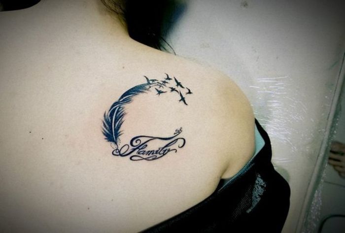 Hình xăm lông vũ với chim bay, chữ "Family" trên vai, phong cách blackwork, chi tiết rõ nét.