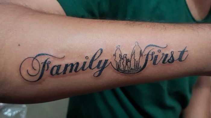 Hình xăm chữ "Family First" trên cánh tay, phong cách chữ đen, chi tiết, ảnh HD.
