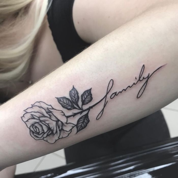 Hình xăm hoa hồng và chữ "family" trên cánh tay, phong cách blackwork, chi tiết rõ nét, độ phân giải HD.