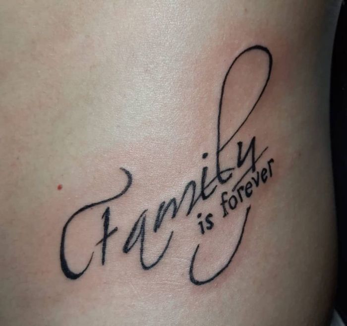 Hình xăm chữ "Family is forever" phong cách blackwork trên lưng, ảnh HD chi tiết.