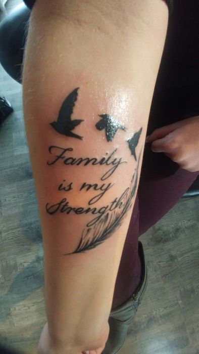 Hình xăm chữ "Family is my strength" với chim bay, phong cách blackwork trên tay, độ phân giải HD.
