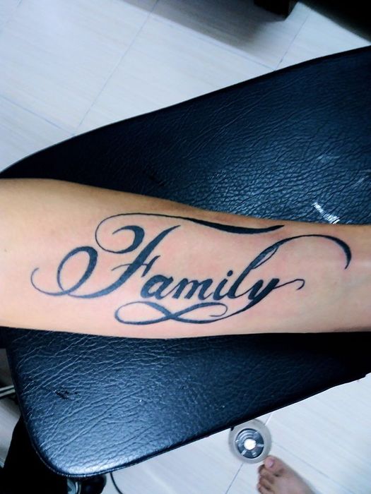 Hình xăm chữ "Family" trên cánh tay, phong cách thư pháp, chi tiết rõ nét, độ phân giải HD.
