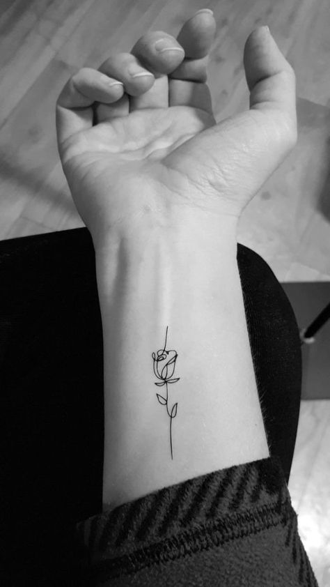 Hình xăm hoa hồng mini phong cách blackwork trên cổ tay, chi tiết tinh tế, ảnh đen trắng, độ phân giải HD.