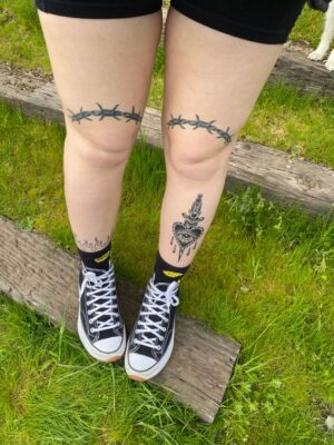 Hình xăm blackwork gai và dao găm trên chân, phong cách tối giản, ảnh độ phân giải HD.