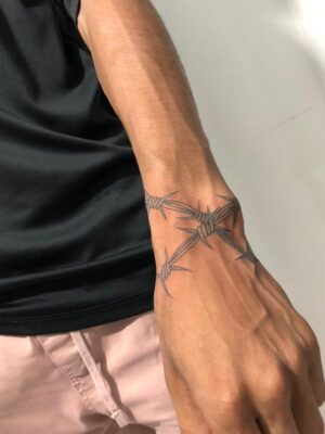 Hình xăm dây thép gai trên cổ tay, phong cách blackwork, chi tiết cao, ảnh độ phân giải HD.
