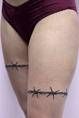 Hình xăm dây thép gai trên đùi, phong cách blackwork chi tiết, ảnh chất lượng HD.