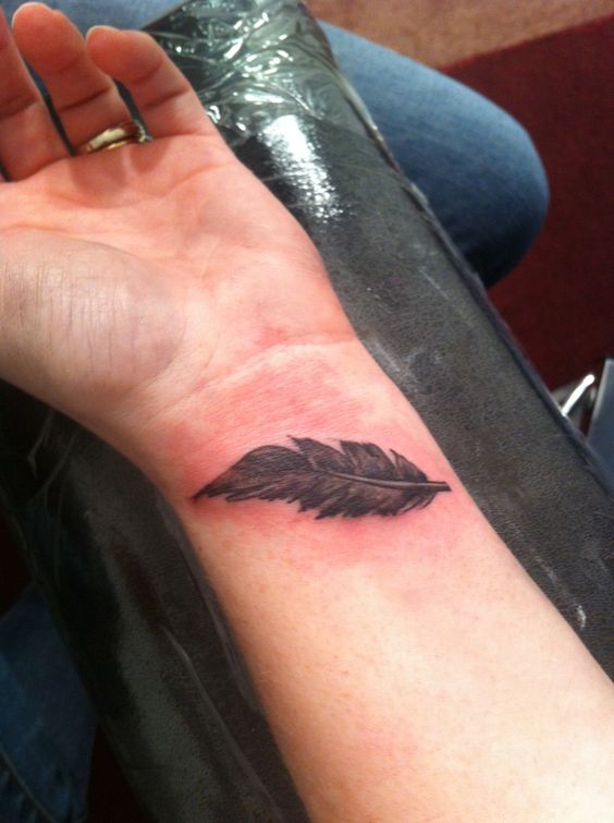 Hình xăm lông vũ blackwork trên cổ tay, chi tiết rõ nét, độ phân giải HD.