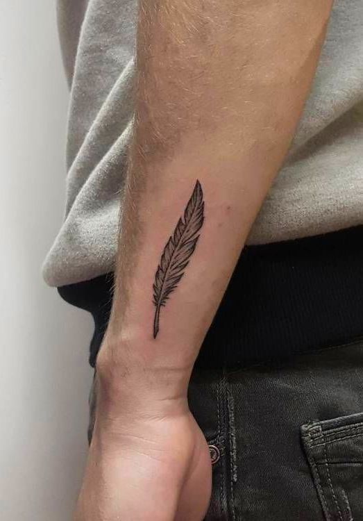 Hình xăm lông vũ trên cánh tay, phong cách blackwork, chi tiết rõ nét, ảnh chất lượng HD.