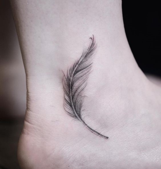 Hình xăm lông vũ mini ở mắt cá chân, phong cách blackwork, chi tiết rõ nét, ảnh HD.