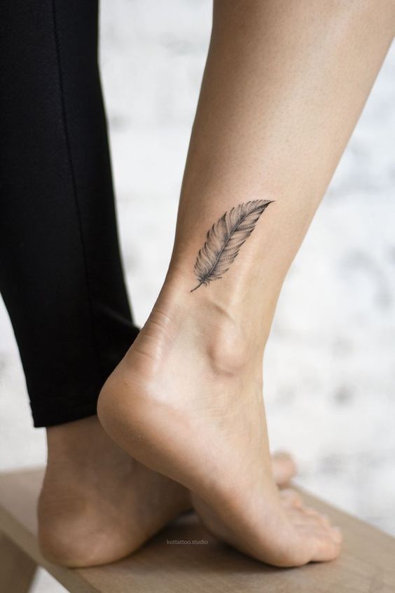 Hình xăm lông vũ mini ở cổ chân, phong cách blackwork, chi tiết rõ nét, ảnh HD.