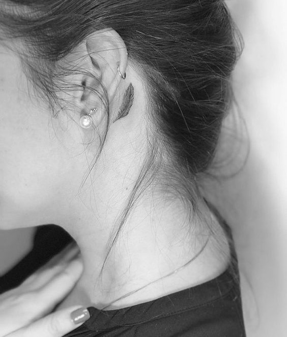 Hình xăm lông vũ mini sau tai phong cách blackwork, ảnh đen trắng chi tiết HD.