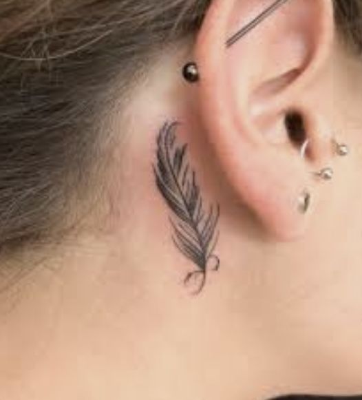 Hình xăm lông vũ mini sau tai, phong cách blackwork, chi tiết rõ nét, ảnh độ phân giải HD.