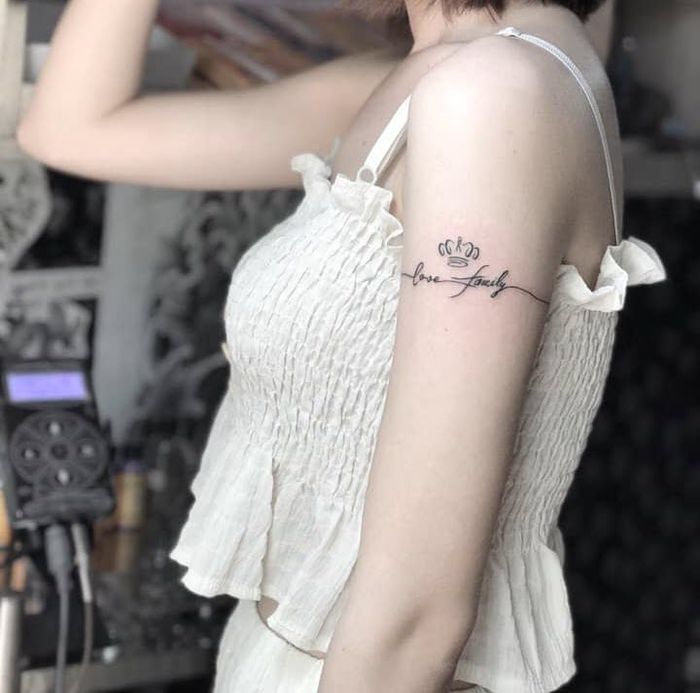 Hình xăm chữ "love family" trên bắp tay, phong cách blackwork, ảnh độ phân giải cao.