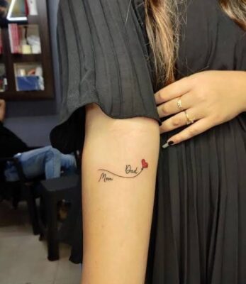 Hình xăm chữ "Mom Dad" với trái tim nhỏ, vị trí cánh tay, phong cách tối giản, độ phân giải HD.