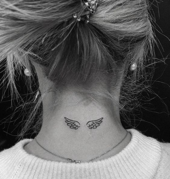 Hình xăm đôi cánh mini ở gáy, phong cách blackwork, chi tiết rõ ràng, ảnh độ phân giải cao.