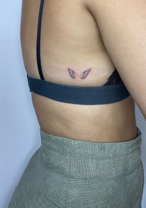 Hình xăm đôi cánh mini, phong cách blackwork, vị trí dưới ngực, ảnh độ phân giải HD.