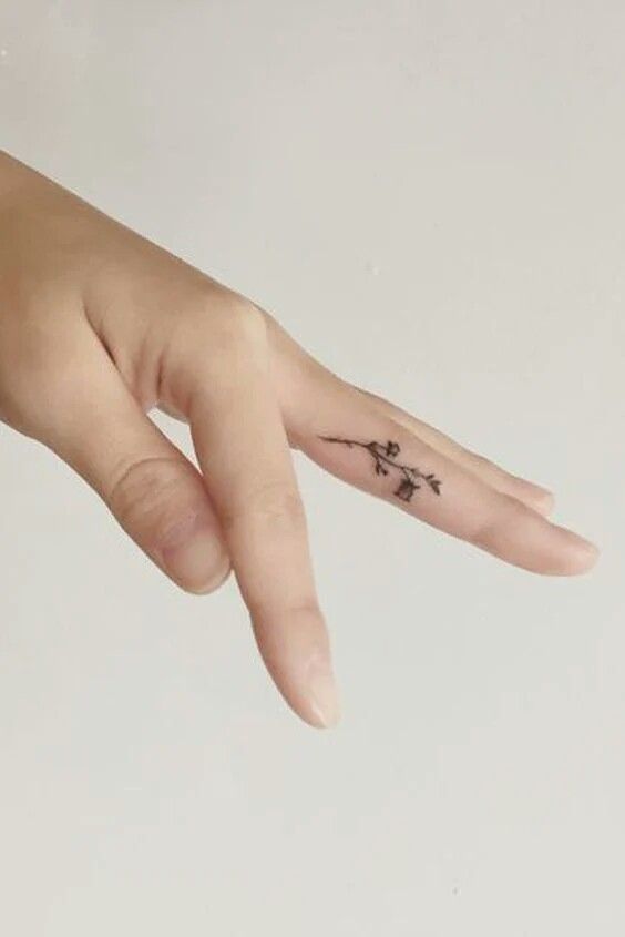 Hình xăm nhánh hoa mini trên ngón tay, phong cách blackwork, độ phân giải HD.