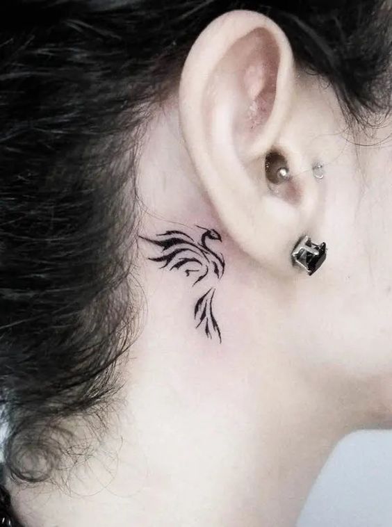 Hình xăm mini phượng hoàng sau tai, phong cách blackwork, chi tiết rõ nét, độ phân giải HD.