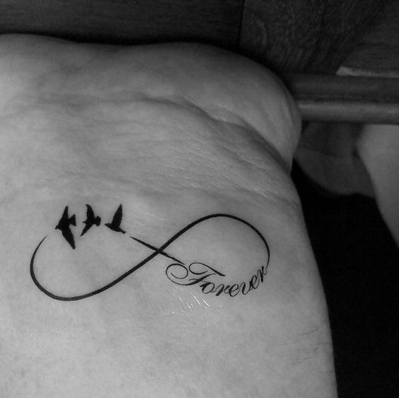 hình xăm mang ý nghĩa sâu sắc Hình xăm vô cực với chữ "Forever" và chim, vị trí cổ tay, phong cách blackwork, độ chi tiết cao, ảnh HD.