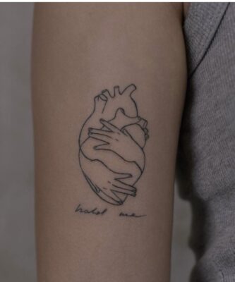 hình xăm trái tim ôm ấp trong vòng tay đầy tình cảm Hình xăm trái tim trên tay, phong cách blackwork tối giản, độ phân giải HD.