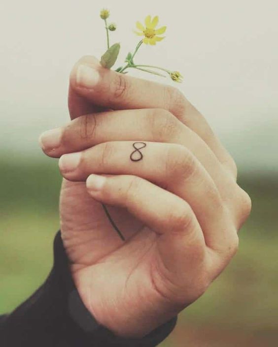 tatoo vô cực nhỏ cho nam Hình xăm số 8 trên ngón tay, phong cách tối giản, ảnh chất lượng cao, tay cầm hoa nhỏ.