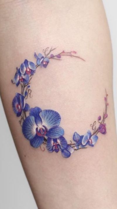 tác phẩm xăm vòng hoa phong lan dịu dàng Hình xăm hoa lan xanh trên cánh tay, phong cách màu nước, chi tiết tinh tế, ảnh HD.