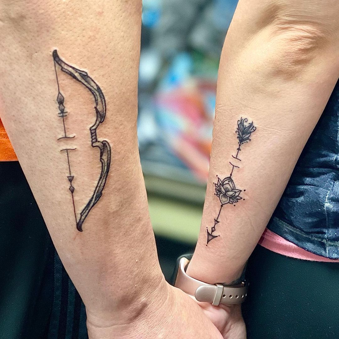 Hình xăm cung tên và hoa văn trên cẳng tay, phong cách blackwork, chi tiết rõ nét, độ phân giải HD.